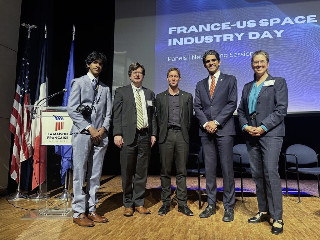 DOC delegates pose with Nicolas Maubert of the French embassy, with a "France-US Space Industry Day" graphic behind them