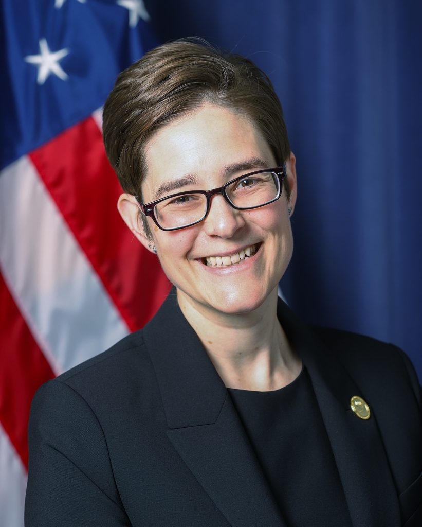 Headshot of Sarah Brothers with U.S. flag in background